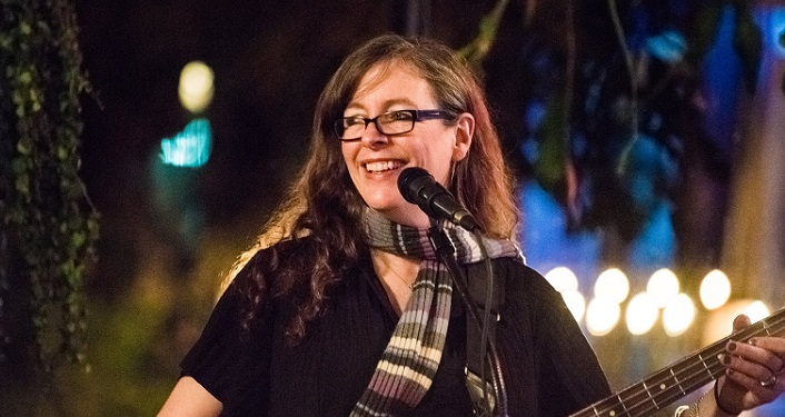 Image of Elizabeth Roth performing at Tradewinds; long brown hair, wearing dark glasses