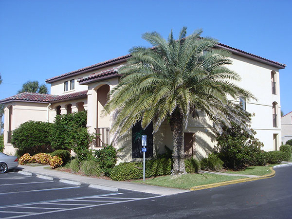 Image contains a handicap parking spot, a hotel, and palm trees.