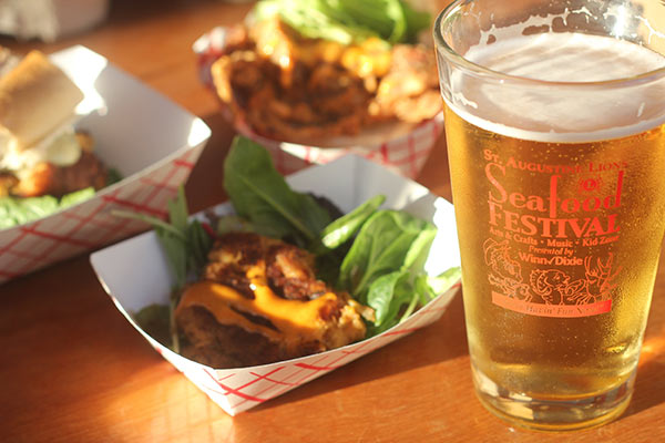 Two bowls of fried shrimp, one bowl with a po' boy, and a glass of beer.