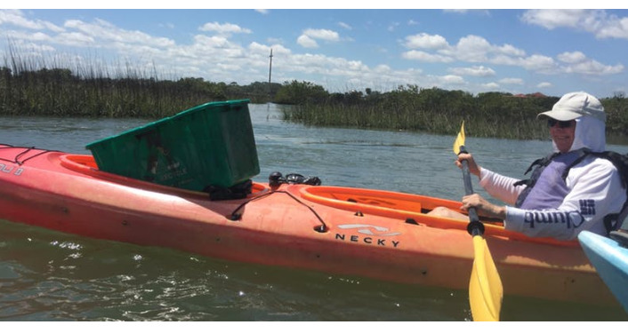 image of kayaker carrying waste receptacleduring Helen Mellon Schmidt Waterway Cleanup