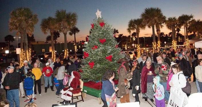 image at St. Augustine Beach Pier Park of Christmas tree with Santa sitting in a chair and lots of people mingling around during Surf Illumination