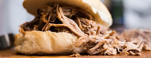 Image contains a pulled pork sandwich on a plate.