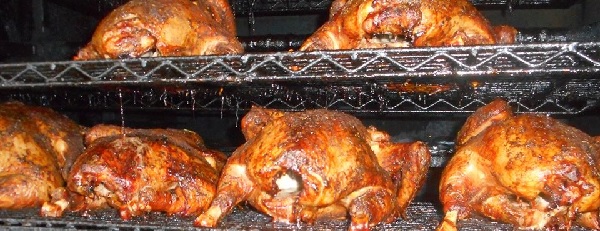 Image contains whole chickens on a BBQ rack.