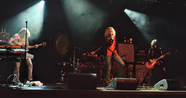 press photo of Zoso standing on stage performing