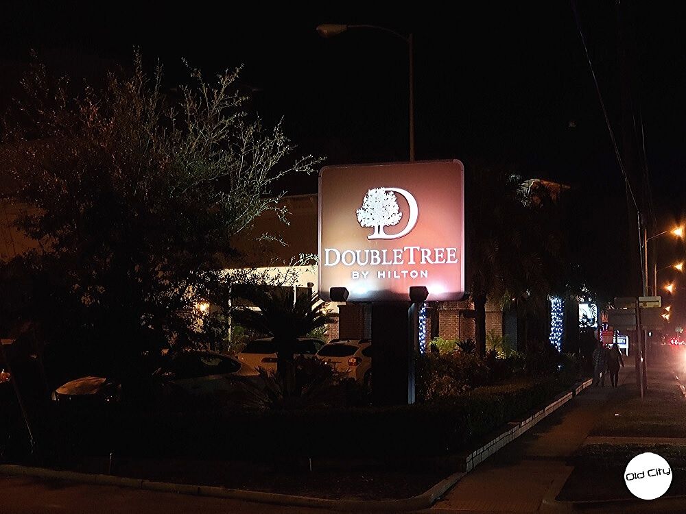 Image contains the front of a hotel, a sidewalk, and trees.