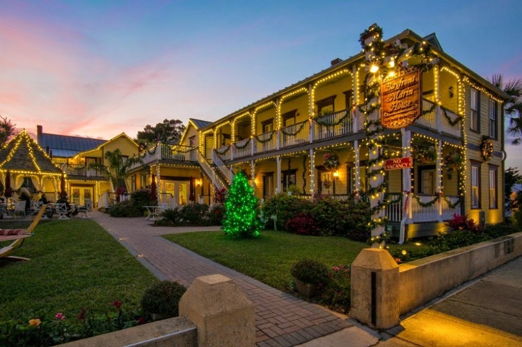 Image contains the front of a hotel adorned in holiday lights.