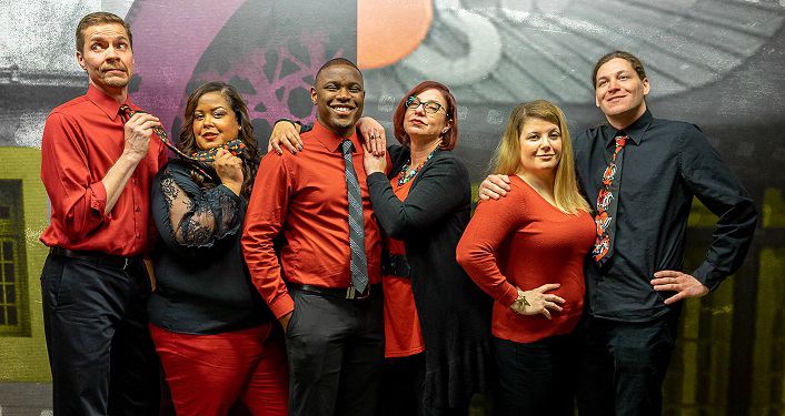 3 couples standing; all wearing either red tops & black slacks or black tops, red slacks