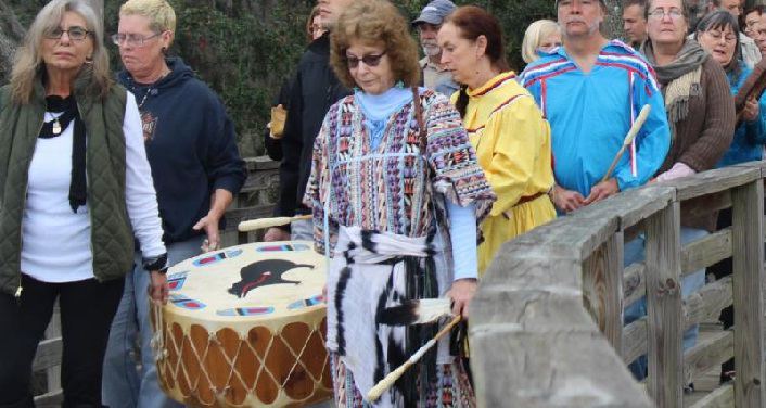 two women carrying drum, followed by several man and women - Annual River Blessing