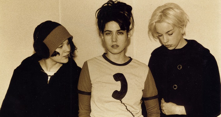 press photo of Pioneer feminist punk band, Bikini Kill; black & white image 3 women, 2 with dark hair, 1 blonde - all 3 weearing casual clothes